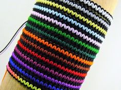 there is a multicolored crochet bracelet on the arm that has a cord attached to it