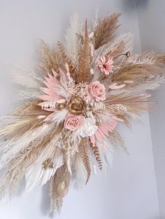 an arrangement of dried flowers and feathers on a wall