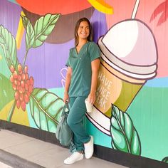 a woman standing in front of a colorful wall holding a bag and smiling at the camera