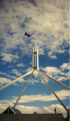 a flag is flying high in the sky above a building with columns and pillars on each side