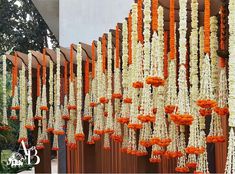 an arrangement of white and orange flowers hanging from the side of a building