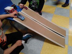 two children playing with toys on the floor in front of a cardboard plane that has been cut into smaller pieces