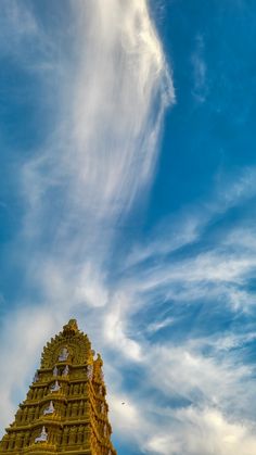 a very tall tower with a clock on it's side under a cloudy blue sky