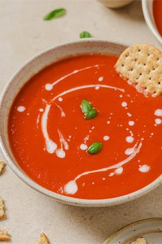 a bowl of tomato soup with crackers on the side