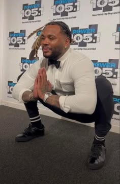 a man in white shirt and black pants sitting on the floor with his hands crossed