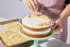 a woman is decorating a cake with icing and crumbs on it