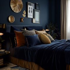 a bedroom with dark blue walls, gold accents and bed linens on the bed