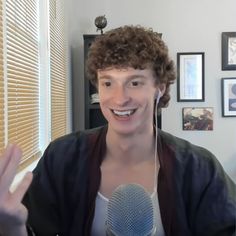 a man with curly hair is holding a microphone in his hands and smiling at the camera