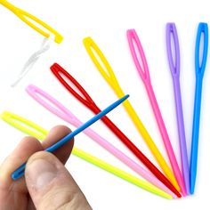 a hand is holding several colored toothbrushes on a white background with one being held by the other