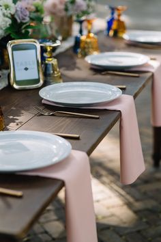 the table is set with plates and place settings for guests to sit down at it