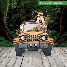 mickey mouse driving in the back of a car on a wooden floor with trees behind it