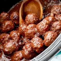 the meatballs are being cooked in the crock pot with a wooden spoon and is ready to be eaten