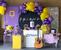 a purple and yellow birthday party with balloons on the wall, guitar in foreground