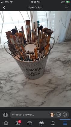 a bucket full of paint brushes sitting on top of a marble counter next to a window