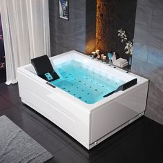 a white bath tub sitting on top of a black tile floor next to a window