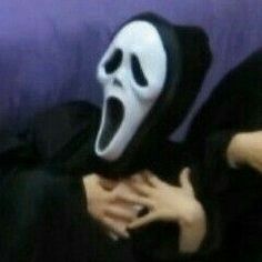 a person wearing a ghost mask sitting on a couch