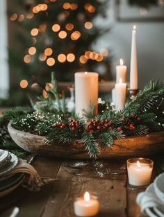 a wooden bowl filled with candles on top of a table next to a christmas tree