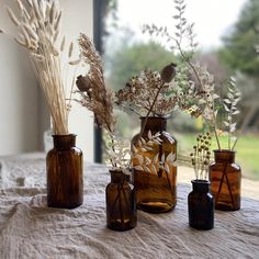 four vases with dried plants in them on a table