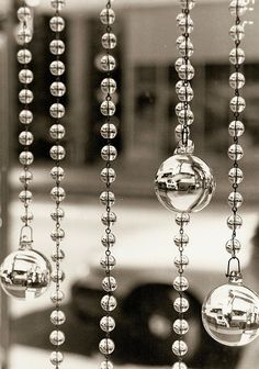 a window with beads hanging from it and a car in the back ground behind it