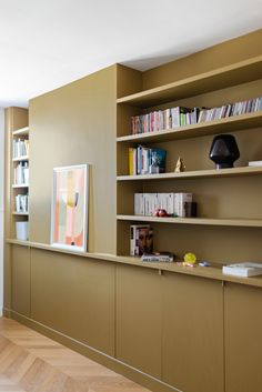 the bookshelves are lined up against the wall in this room with wood flooring