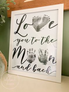 a white frame with black hand prints and the words love you to the moon and back