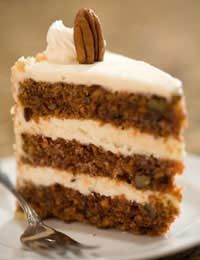 a slice of carrot cake with white frosting and pecans in the middle on a plate