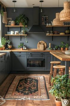 a kitchen with wooden floors and gray cabinets, plants on the shelves above the stove