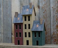 two small houses sitting on top of a wooden table next to a fence with snow flakes