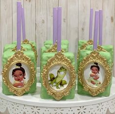 there are three little princess and frog decorations on the cake stand with candles in front of them