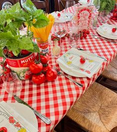 the table is set with red and white gingham cloths, plates, utensils, and tomatoes