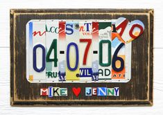 a license plate is displayed on a white wooden wall with hearts and words written below it