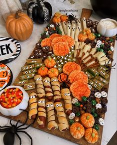 a table topped with lots of halloween treats and candy bar decorations on top of a wooden cutting board