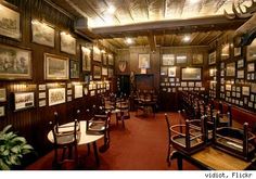 an old fashioned restaurant with many tables and pictures on the wall above them, along with chairs