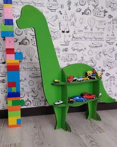 there is a green toy dinosaur next to a wall with cars on it and a lego tower