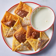 some desserts are on a plate next to a cup of milk and a glass of milk