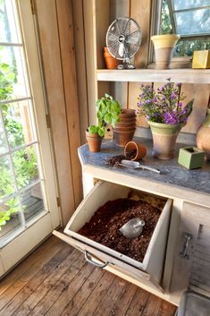 an open drawer with plants in it on top of a counter