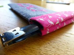 a close up of a pair of scissors on top of a wooden table next to a pink and blue case