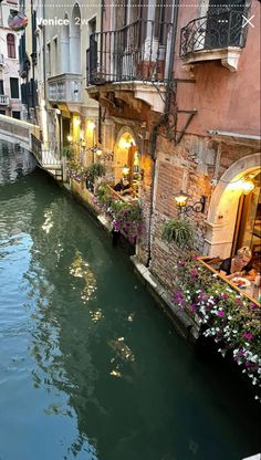 a narrow canal runs between two buildings with balconies and flowers on the balcony