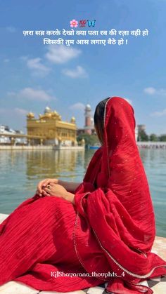 a woman in a red sari sitting on the edge of a body of water