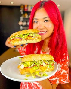 a woman with red hair holding two sandwiches