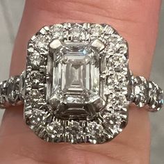 a close up of a person's hand holding a ring with an emerald and diamonds on it