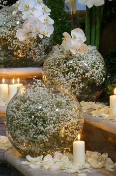 three vases filled with white flowers and lit candles