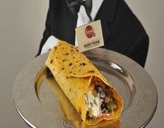 a man sitting at a table in front of a silver plate with a burrito on it