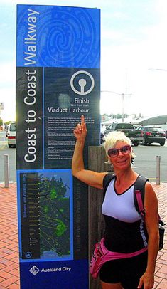 a woman is standing next to a sign