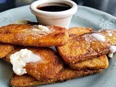 some french toast on a blue plate with butter and syrup in the middle, next to a cup of ketchup