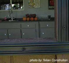 the reflection of a kitchen in a mirror on a table with drawers and cupboards