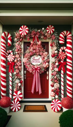 a christmas wreath with candy canes hanging on the front door and decorations around it