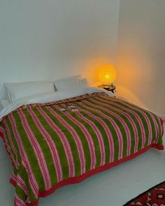 a bed sitting in the corner of a room with a lamp on top of it