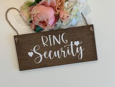 a sign that says ring security hanging on a wall with flowers in front of it