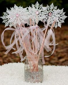 a glass vase filled with snowflakes and pink ribbon on top of a table